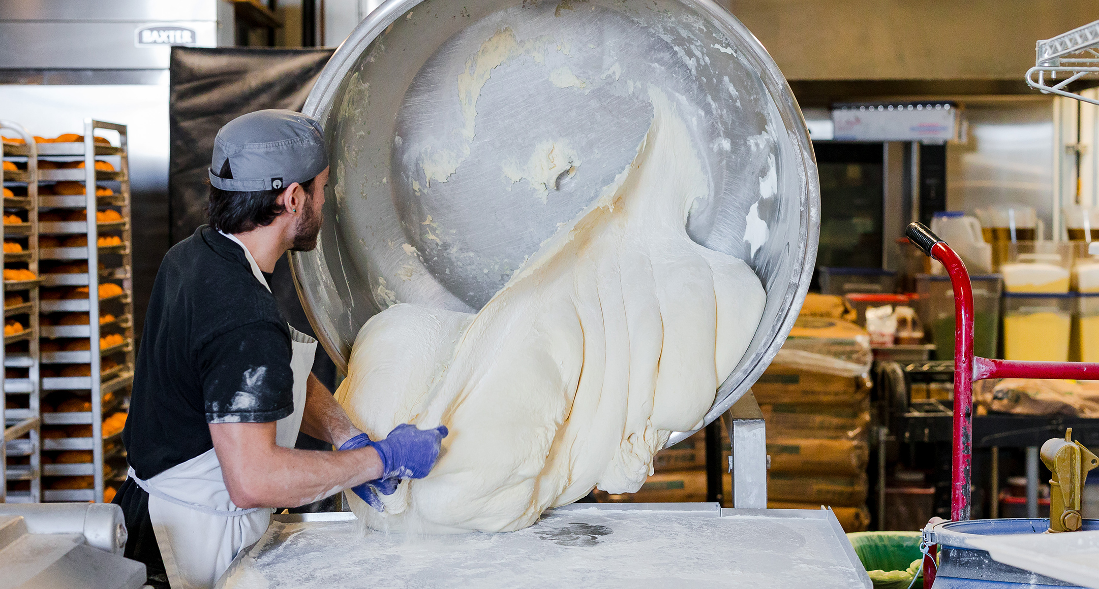 A large batch of Bowery Bagels dough going from mixer onto a workstation.