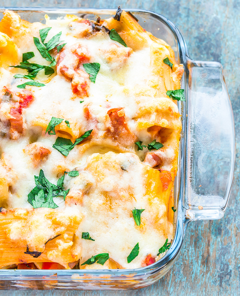 a glass casserole dish with baked rigatoni covered in cheese.