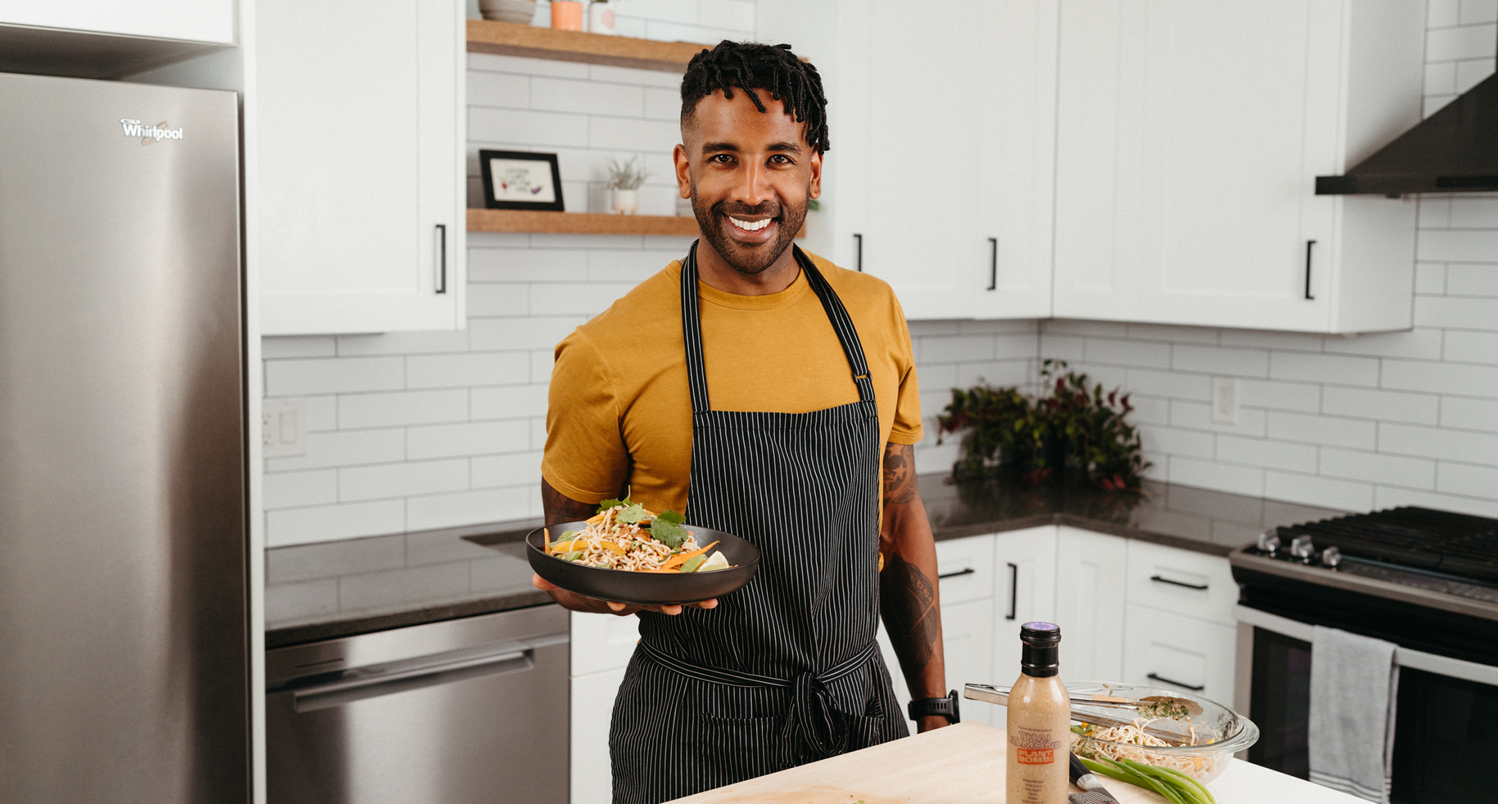 Portland chef Rajiv Harry of Plant Bomb sauces in a kitchen holding a bowl of food. 