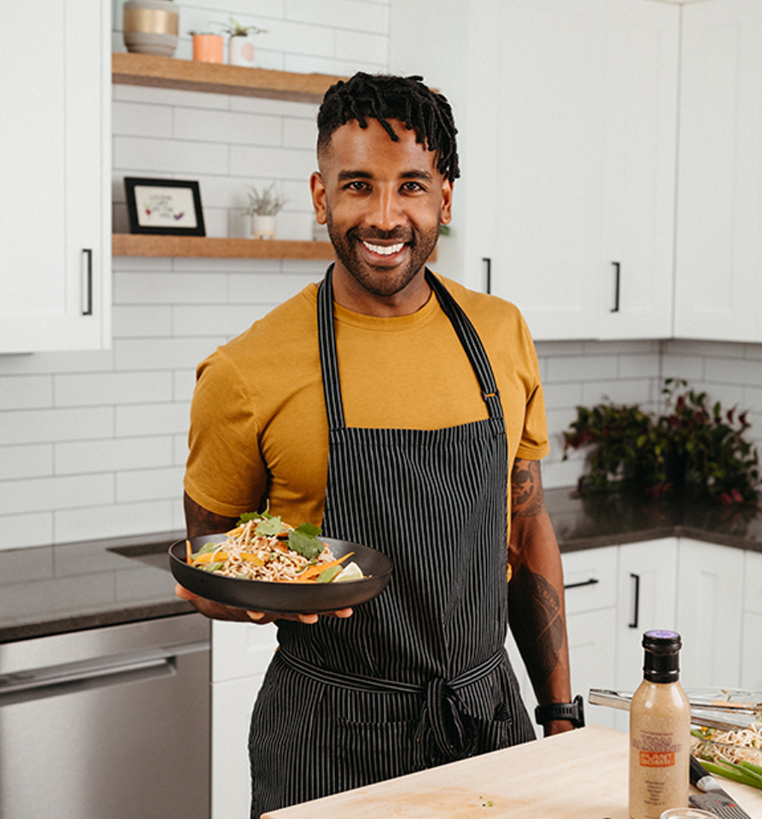 An image of Chef and health and wellness coach Rajiv Harry of Plant Bomb with a bowl of food featuring one of his sauces. 