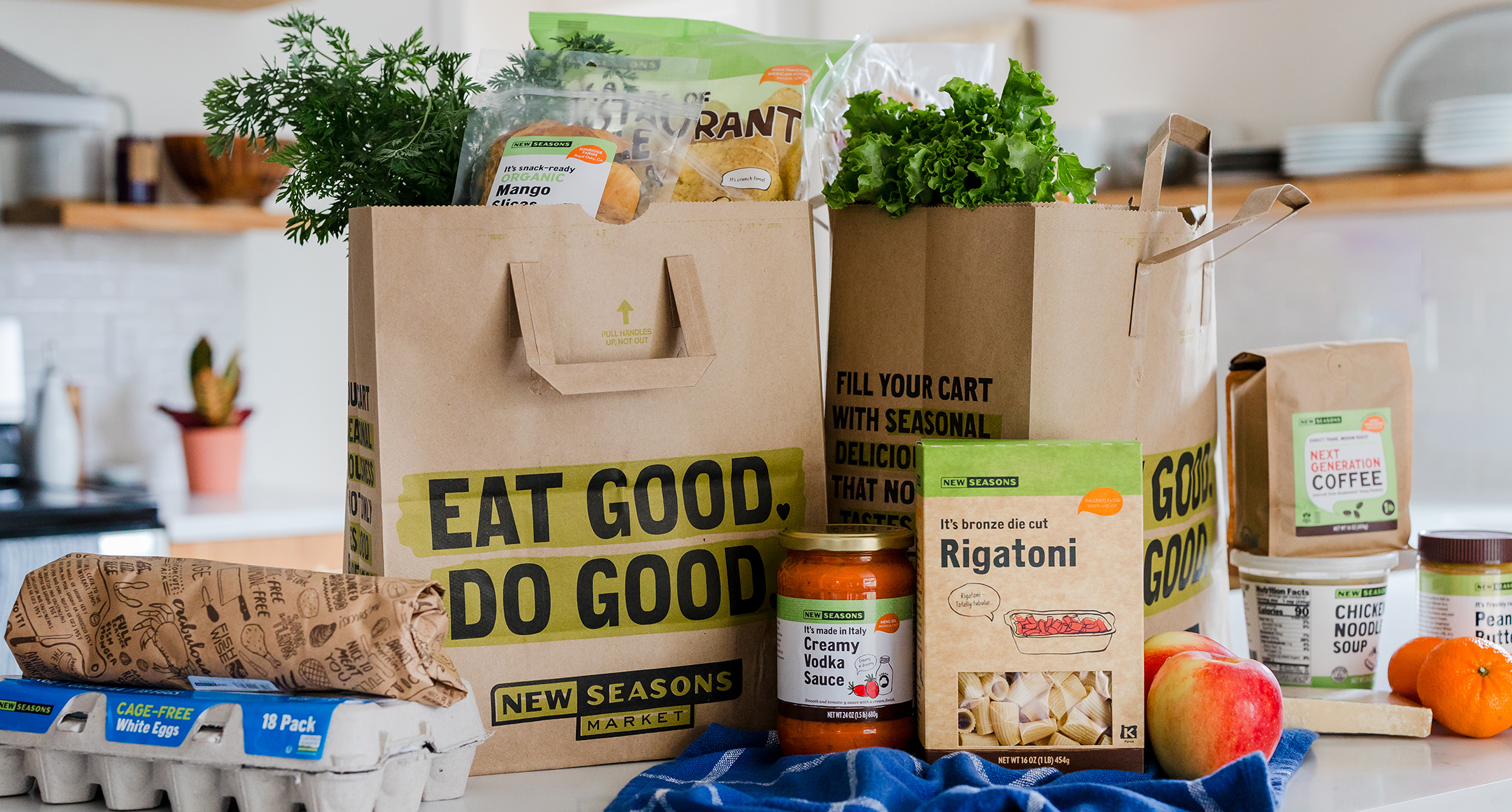 A countertop loaded with two New Seasons paper grocery bags and New Seasons products.