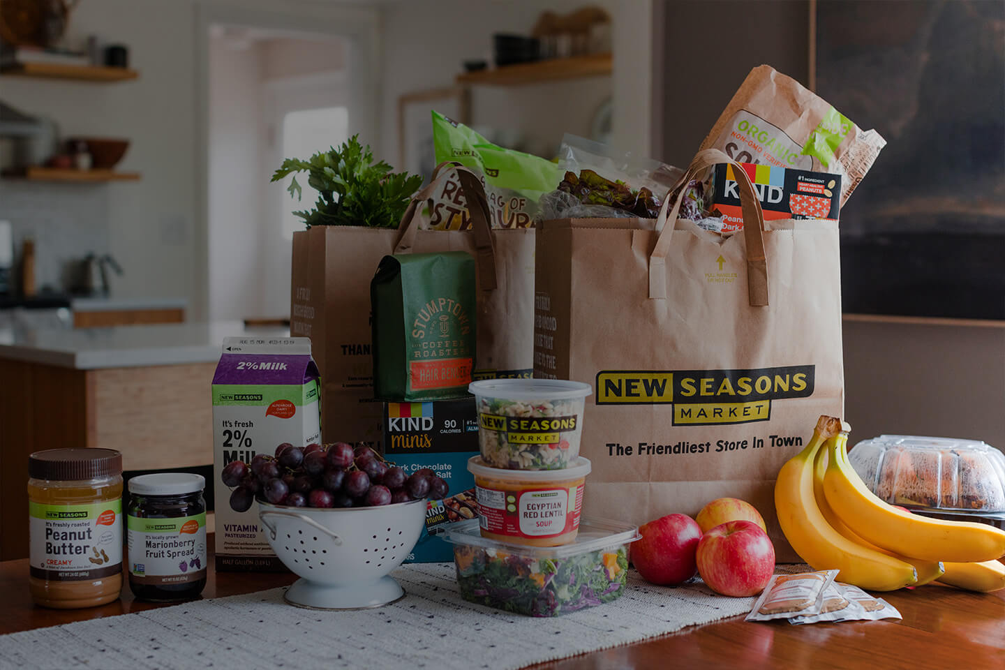 Grocery bag with fruit, chips, snacks and other items on a kitchen counter.