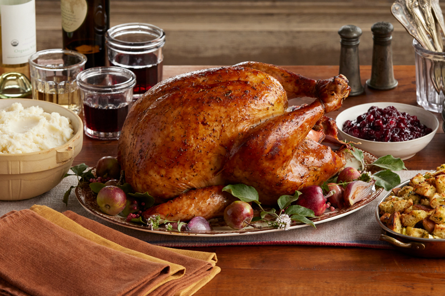 A festive holiday meal with roasted turkey, cranberry sauce, mashed potatoes, bread stuffing, gravy, and white wine.