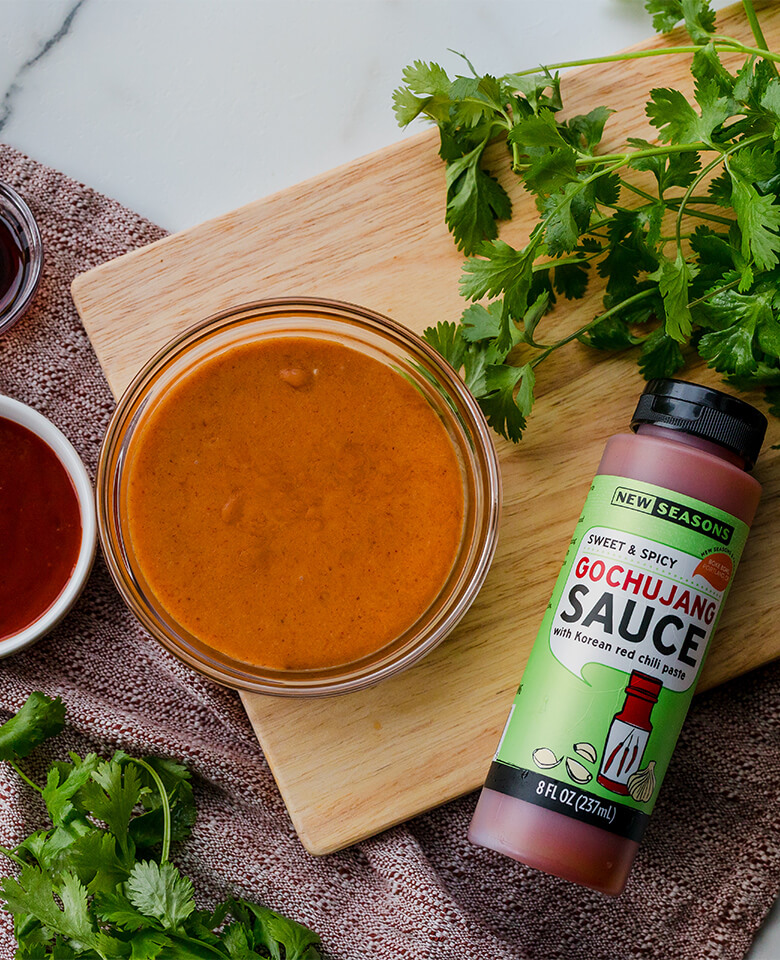 New Seasons all-purpose gochujang sauce arranged with a bowl of gochujang butter and a smaller bowl of soy sauce on a marble surface