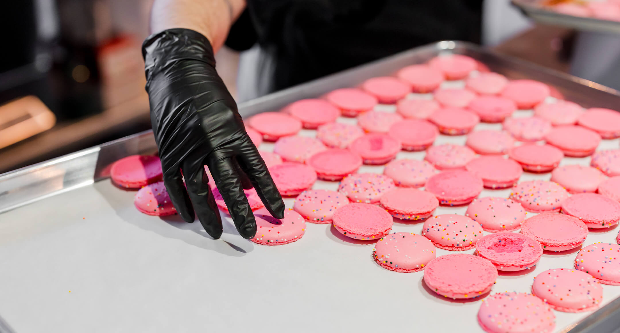 Farina Bakery pink macaron halves placed on a sheet pan before being filled.