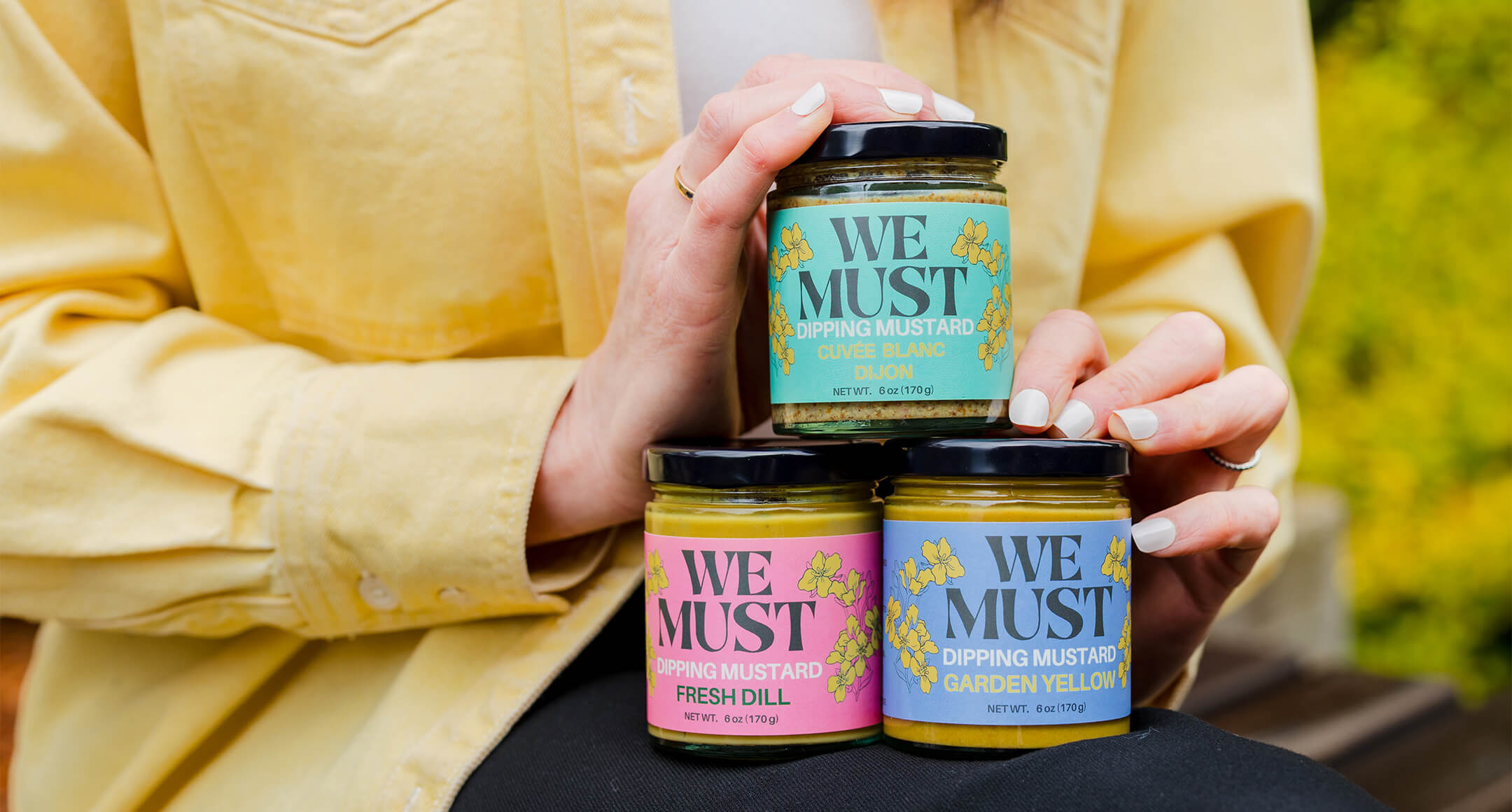 three jars of We Must mustard including dijon, garden yellow and fresh dill flavors.