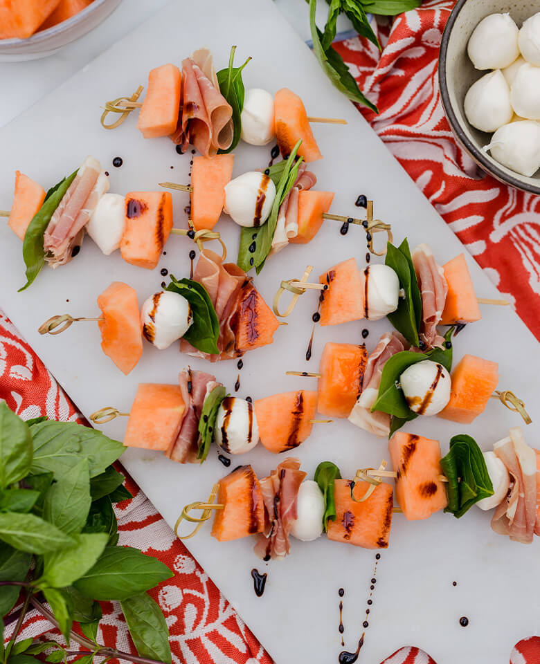 Summer skewers with cantaloupe, prosciutto, fresh mozzarella, and basil.
