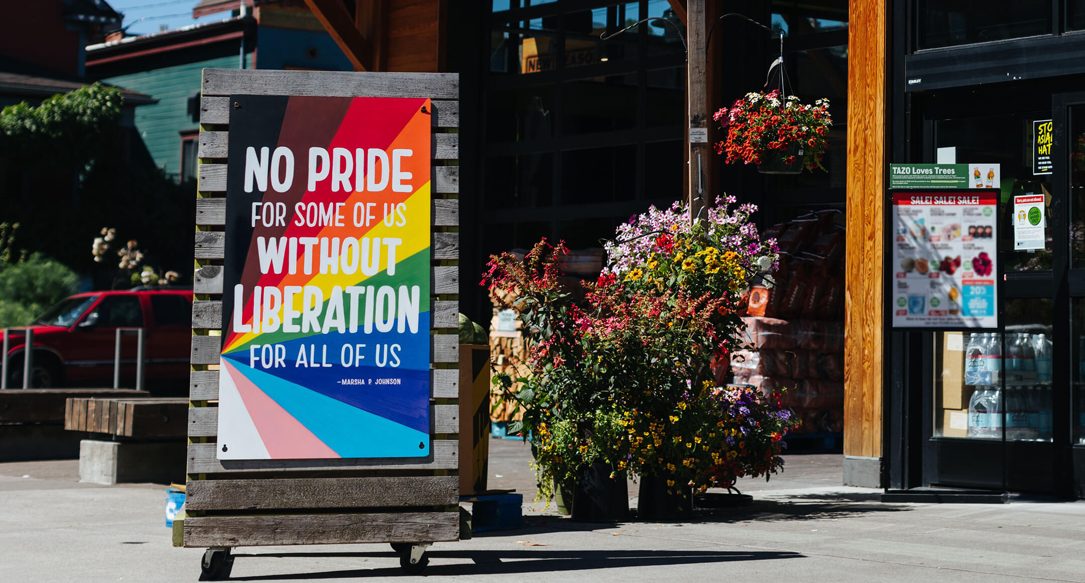 A hand-painted Pride Month sign outside of New Seasons Market that reads: No Pride for Some Without Liberation for All of Us. 