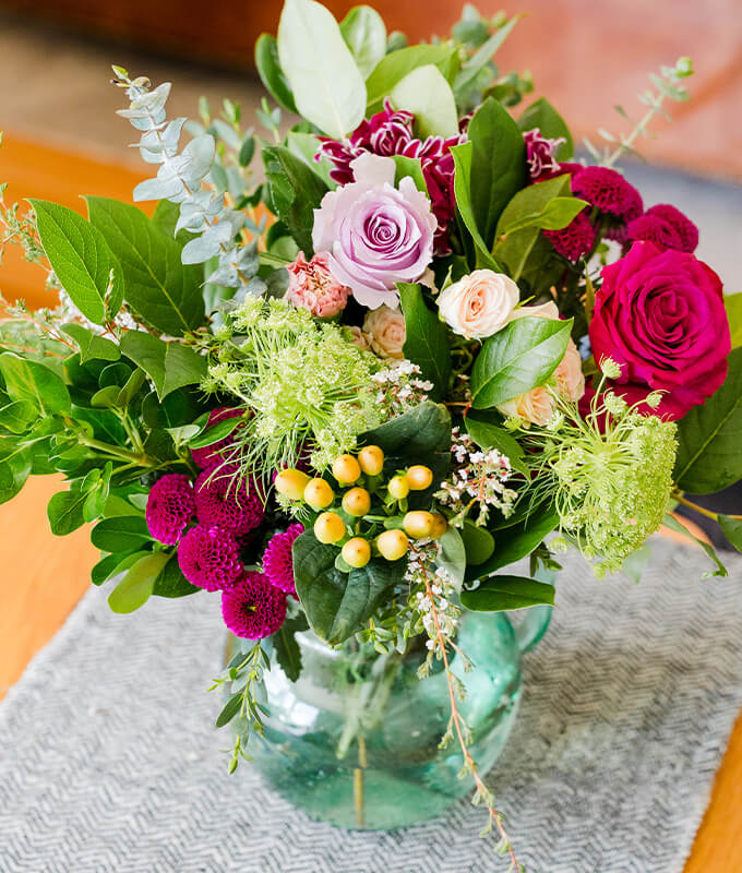 An image of a floral arrangement in a vase on a table.