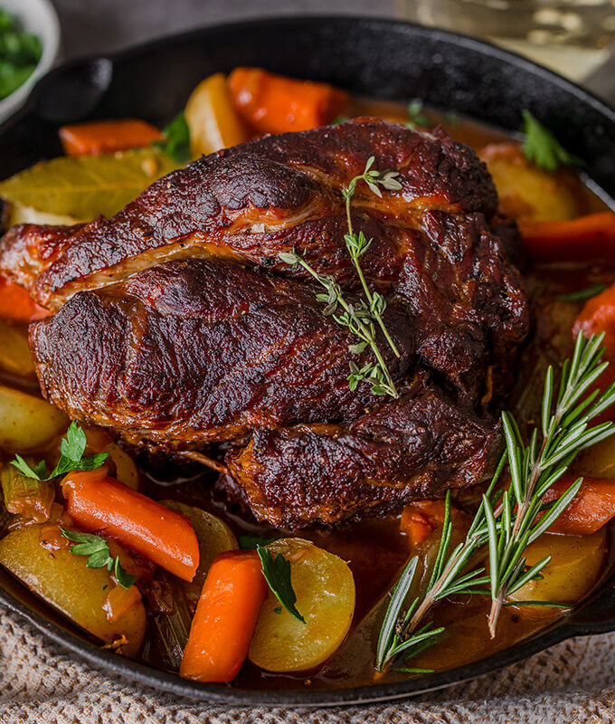a roast in a cast iron pan with vegetables