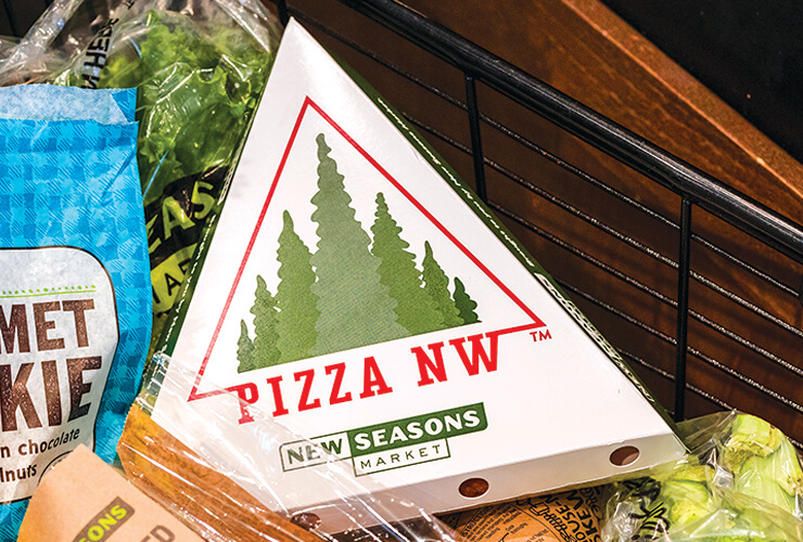 A pizza-by-the-slice box with a New Seasons PizzaNW logo on it for to-go slices.