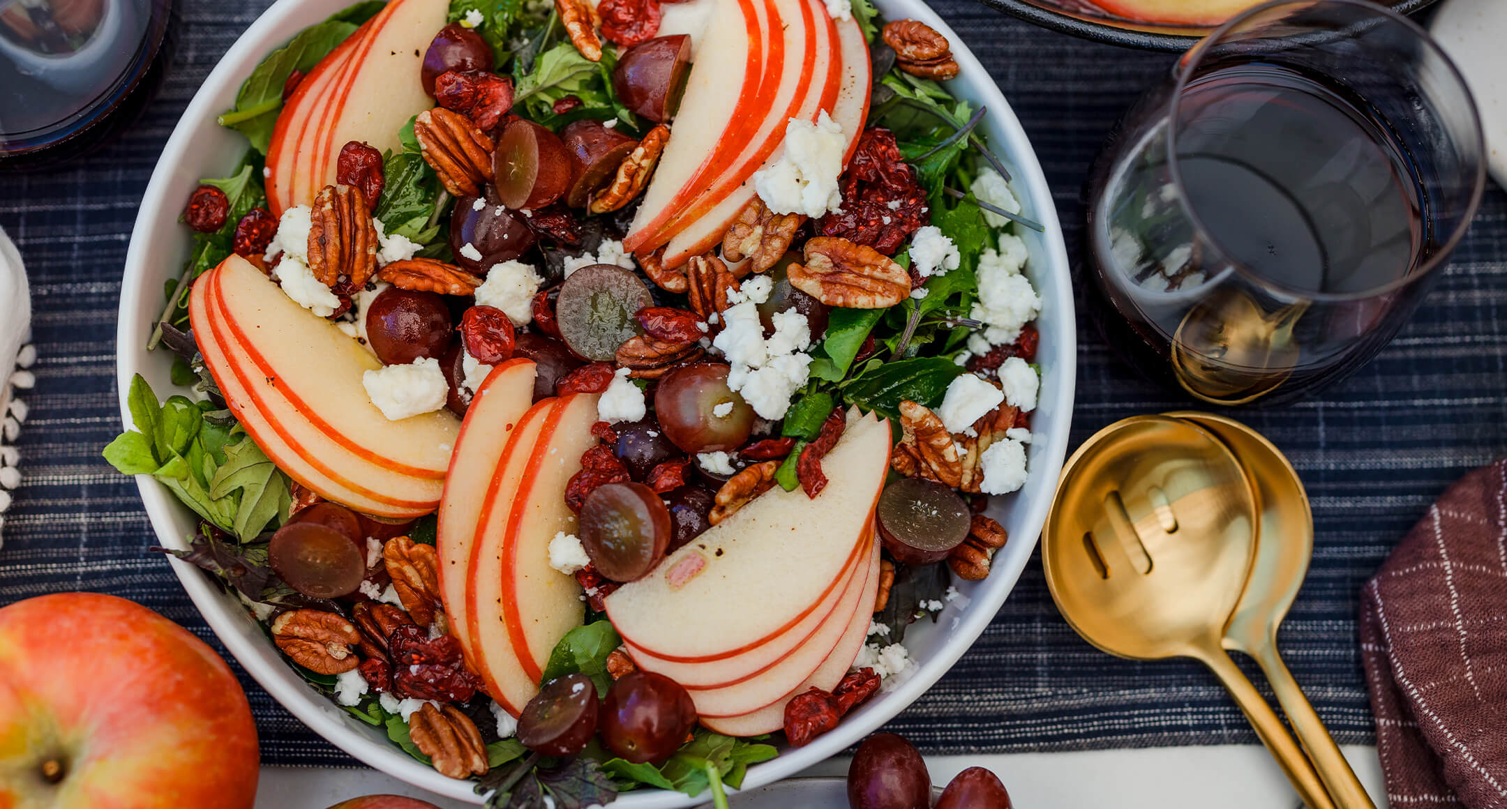 A salad in a bowl featuring sliced apples, grapes, and goat cheese crumbles. 