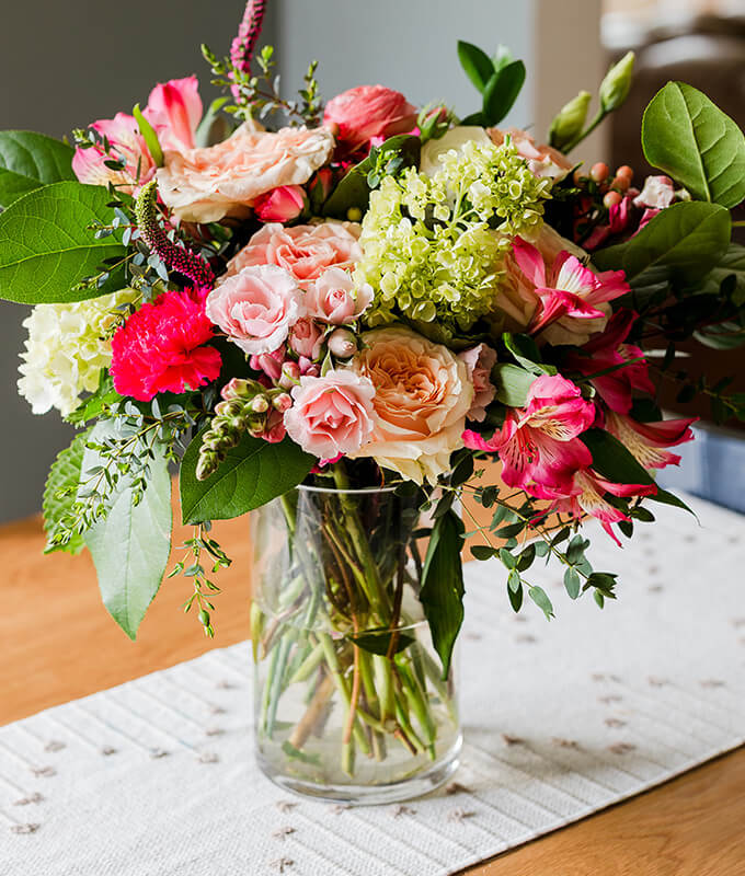 a beautiful fresh bouquet of flowers in a clear vase with water on a table