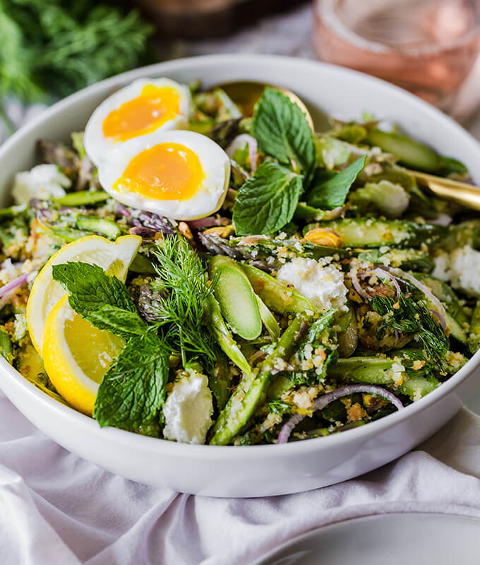 A spring raw asparagus salad mixed with goat cheese, fresh herbs, pistachios, toasted breadcrumbs topped with mint, dill, and a soft boiled egg.