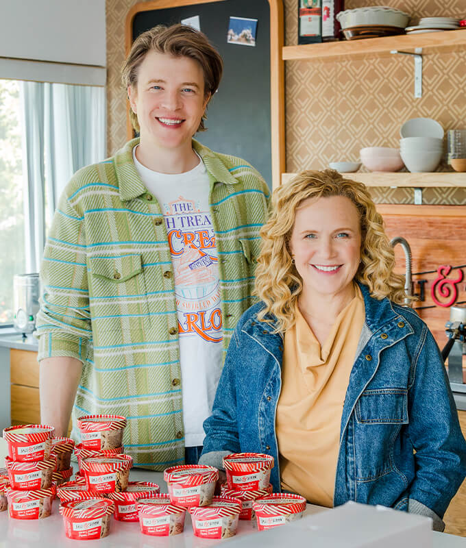 Two people from Salt & Straw standing and smiling with a pile of Salt & Straw half pints of ice cream.