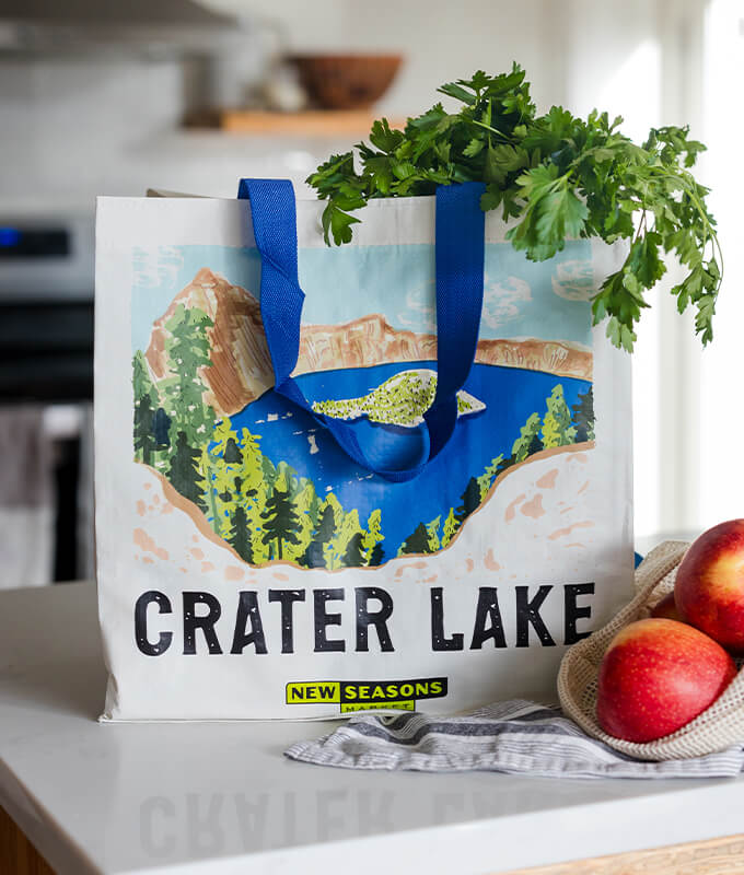 An image of a reusable bag on a counter with produce hanging out. 