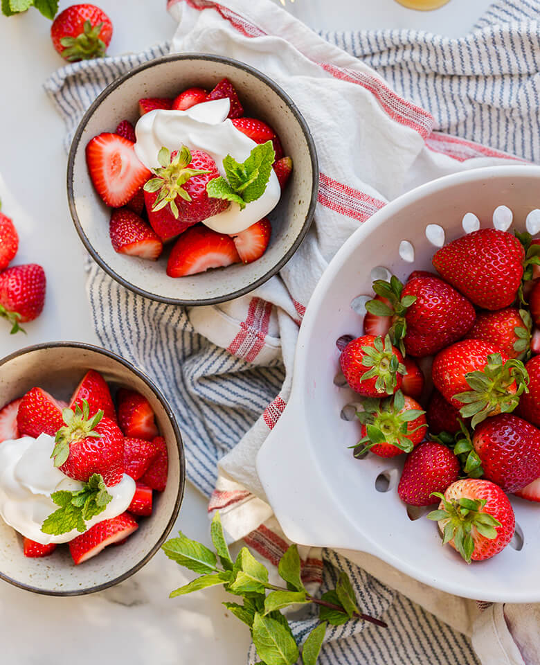strawberries in bowls topped with cream