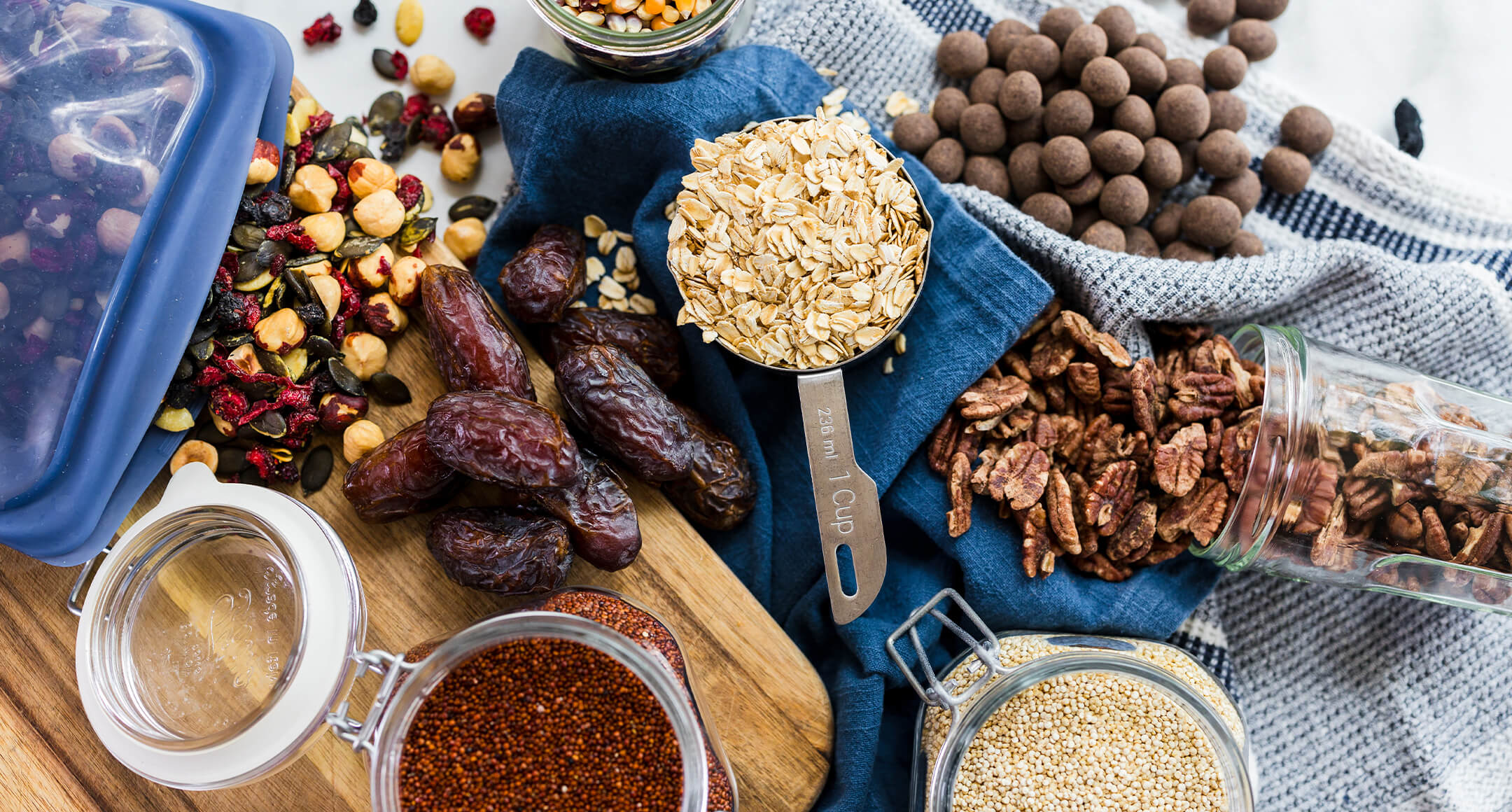 Bulk food items displayed on a table along with reusable containers. 