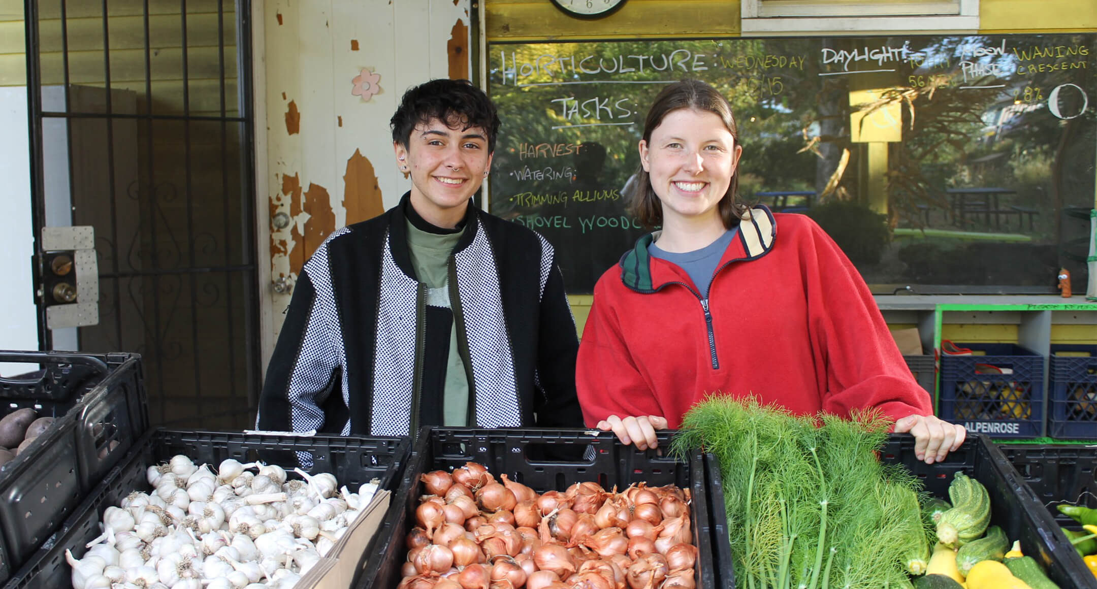 Two individuals with fresh produce from Serendipity Center.